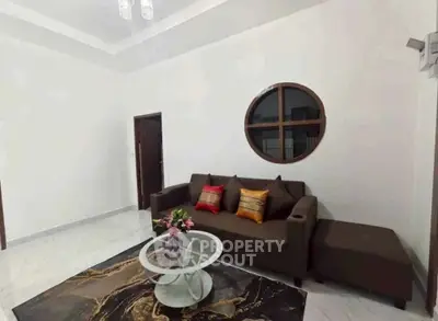 Modern living room with stylish sofa and unique round window design.