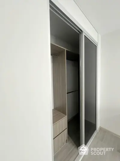 Modern walk-in closet with sliding doors and sleek wooden finish.