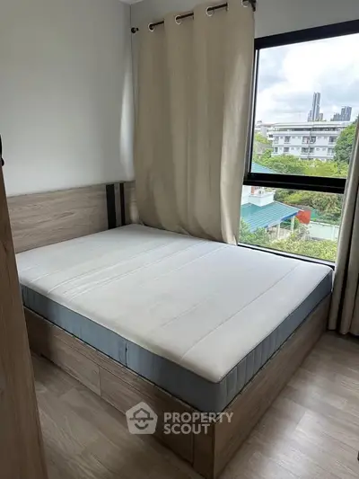 Cozy bedroom with large window offering city view, featuring a comfortable bed and modern decor.