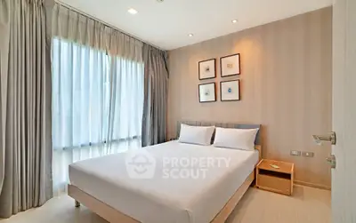 Modern bedroom with elegant decor and natural light, featuring a comfortable bed and stylish wall art.