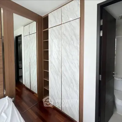 Modern bedroom with elegant wooden flooring and sleek built-in wardrobe