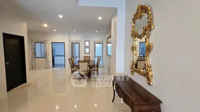 Elegant dining area with ornate mirror and polished floors in spacious home