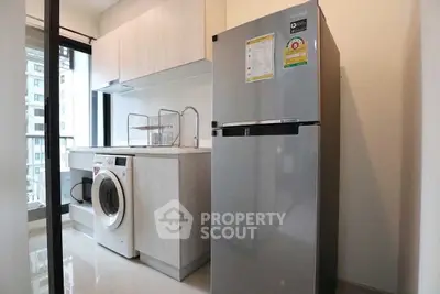 Modern kitchen with washing machine and fridge in a sleek apartment setting.