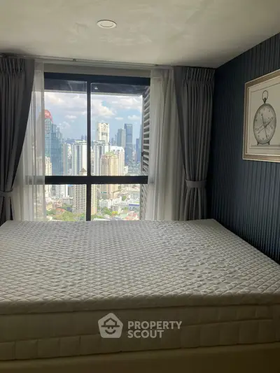 Cozy bedroom with city view, featuring a large window and elegant decor.