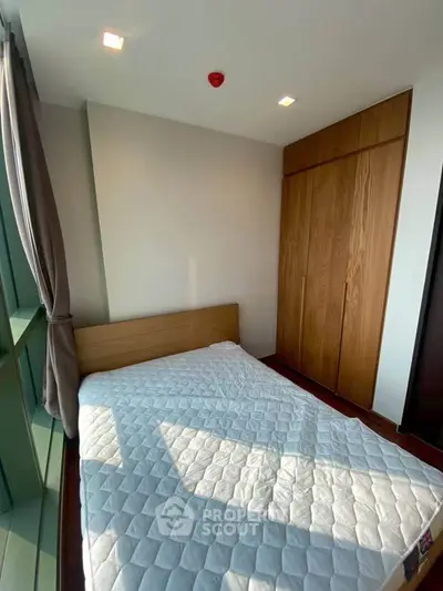 Cozy bedroom with large window and built-in wooden wardrobe