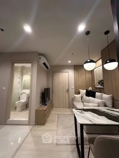 Modern living room with open layout and stylish decor, featuring a cozy dining area and sleek lighting.