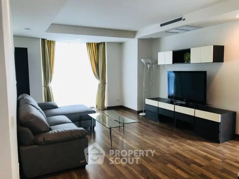 Spacious modern living room with sleek furniture and large window for natural light.