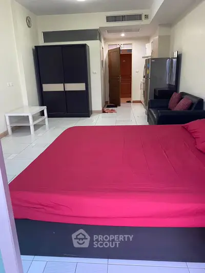 Spacious studio apartment with modern furnishings and open layout, featuring a cozy bed and sleek kitchen area.