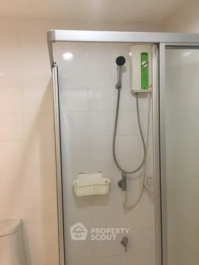 Compact bathroom shower area with modern fixtures and white tiles.