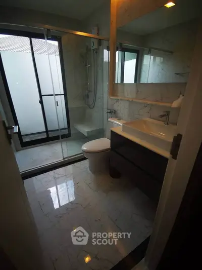 Modern bathroom with marble flooring and glass shower enclosure