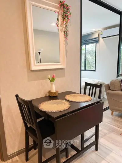 Cozy dining area with elegant table and chairs, mirror decor, and view into a stylish living room.