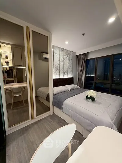 Modern bedroom with elegant decor and city view, featuring a cozy bed and stylish mirrored wardrobe.