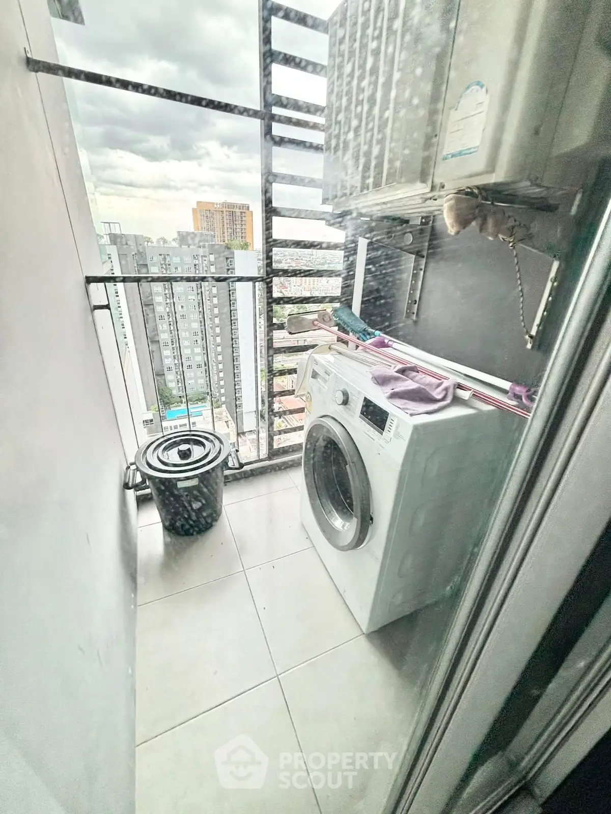 Compact balcony with washing machine and city view, perfect for urban living convenience.