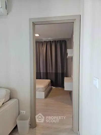 Cozy apartment interior with a view into a minimalist bedroom, featuring neutral tones and modern design.