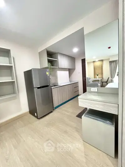 Modern kitchen with sleek cabinetry and stainless steel fridge in a stylish apartment.
