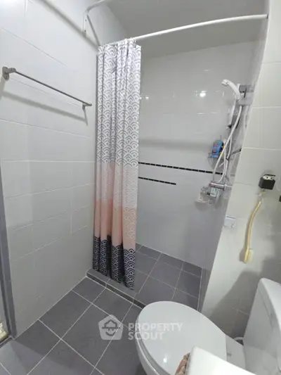 Modern bathroom with shower curtain and tiled floor in a contemporary home.