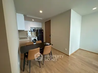 Modern dining area with sleek kitchen and wooden flooring in a contemporary apartment.