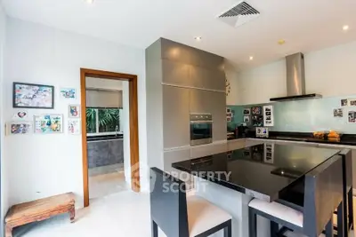 Modern kitchen with sleek design and open layout, featuring a black countertop and stainless steel appliances.