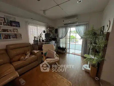 Cozy living room with leather sofa, home office setup, and sliding glass doors to patio.