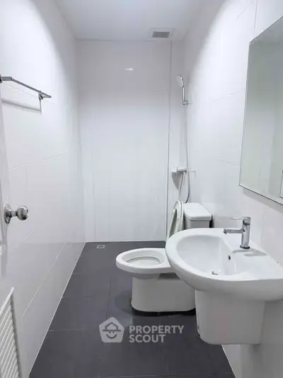 Modern minimalist bathroom with sleek fixtures and white tiles.