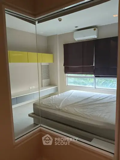 Modern bedroom with large window and air conditioning, featuring sleek built-in storage and minimalist design.