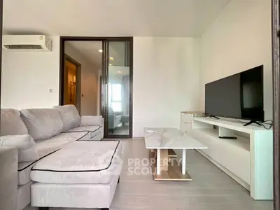 Modern living room with sleek furniture and large TV in a cozy apartment.