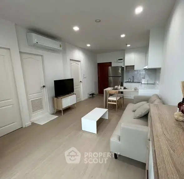 Modern living room with open kitchen, stylish furniture, and bright lighting.