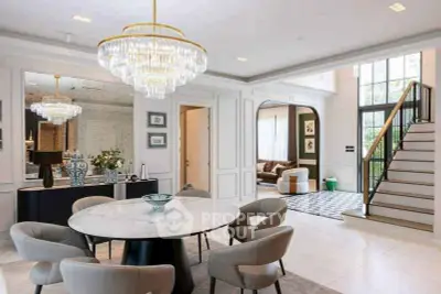 Luxurious dining area with elegant chandelier and open layout leading to a stylish living room.