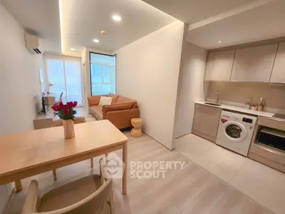 Modern open-plan living room and kitchen with stylish furniture and appliances in a cozy apartment.
