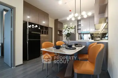 Modern kitchen with sleek design, featuring orange chairs and elegant lighting.