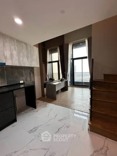 Modern duplex interior with stylish kitchen and spacious living area, featuring large windows and elegant staircase.