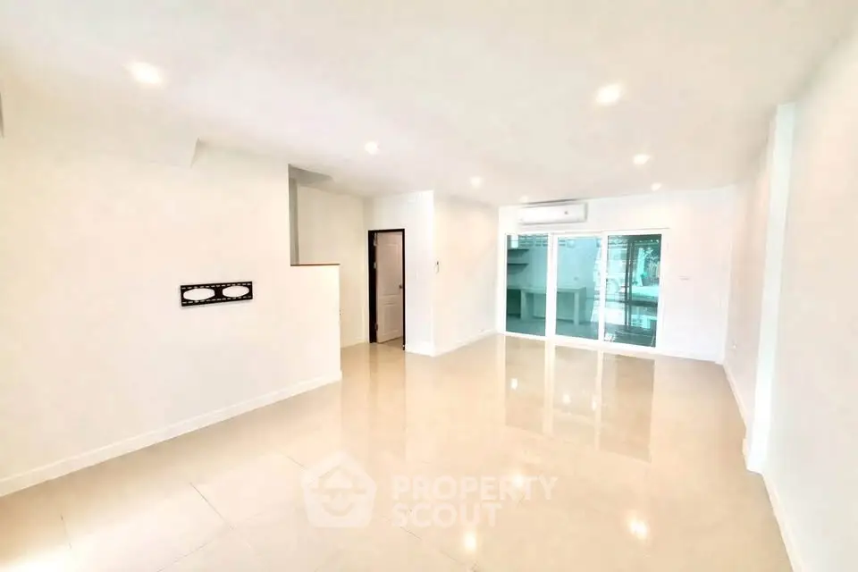 Spacious modern living room with glossy tiled floors and large windows for natural light.