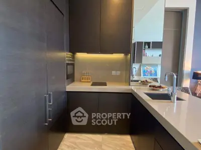 Modern kitchen with sleek dark cabinetry and built-in oven, featuring a stylish open layout.