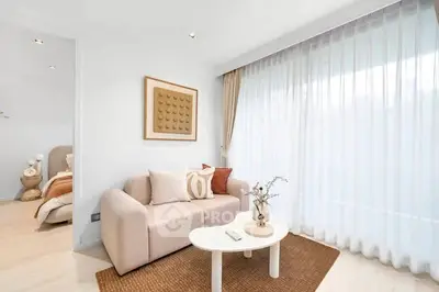Modern living room with cozy sofa and elegant decor, featuring natural light through sheer curtains.