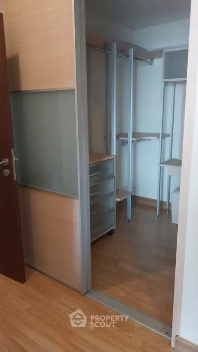 Spacious walk-in closet with wooden flooring and modern shelving.
