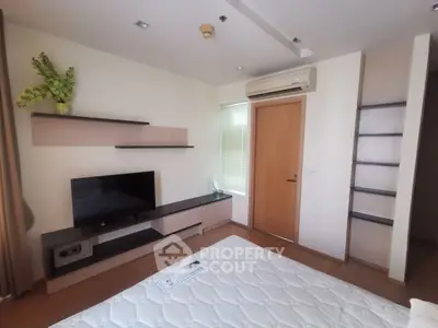 Modern bedroom with sleek TV stand and air conditioning, featuring minimalist decor and natural light.