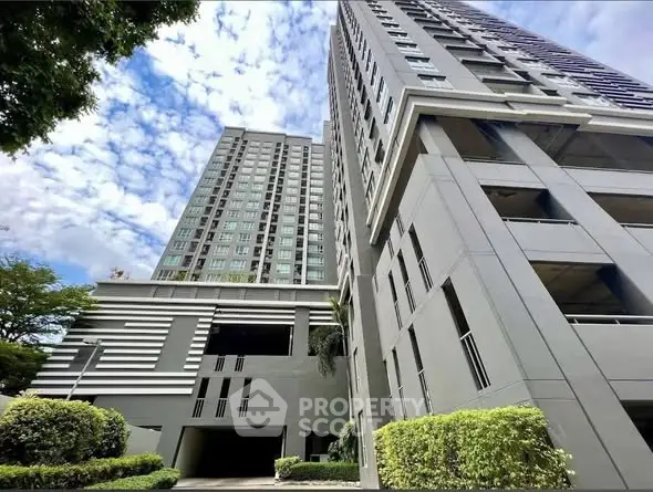 Modern high-rise residential building with lush greenery and clear blue sky.