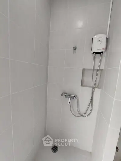 Modern bathroom shower area with sleek tiles and water heater