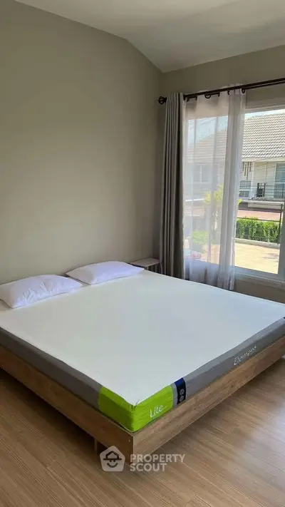 Spacious bedroom with large window and modern decor, offering natural light and a serene atmosphere.