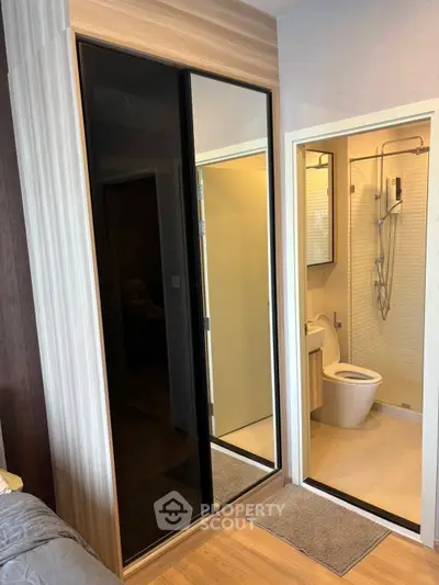 Modern bedroom with ensuite bathroom featuring sleek design and mirrored wardrobe doors.