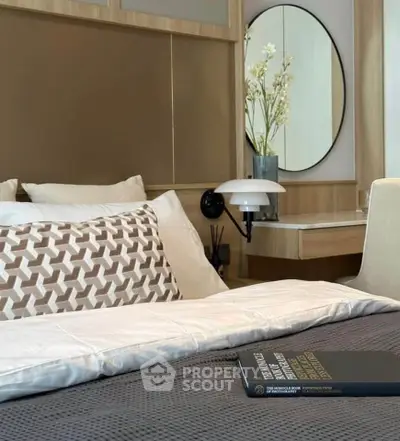 Elegant bedroom with modern decor, featuring a stylish bed, decorative pillows, and a chic vanity mirror.