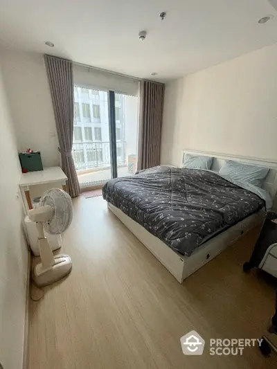 Spacious and well-lit bedroom with large windows offering ample natural light, complemented by elegant drapery and a comfortable bed, perfect for restful nights.