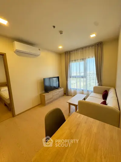 Modern living room with cozy sofa, TV, and large window offering scenic views.