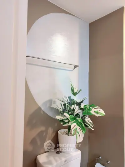 Stylish bathroom with modern decor and potted plant on toilet tank.