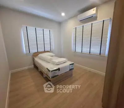 Cozy minimalist bedroom with wooden flooring and air conditioning