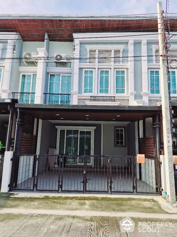 Modern townhouse exterior with gated entrance and large windows