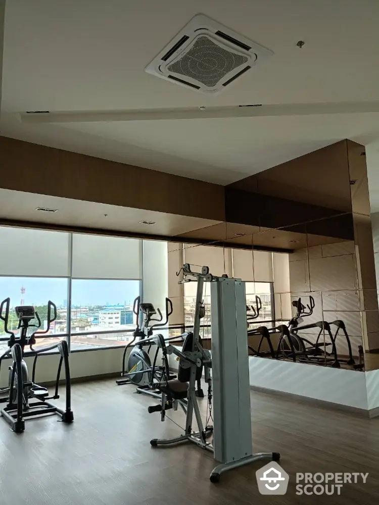 Modern gym with exercise equipment and city view in luxury apartment building.