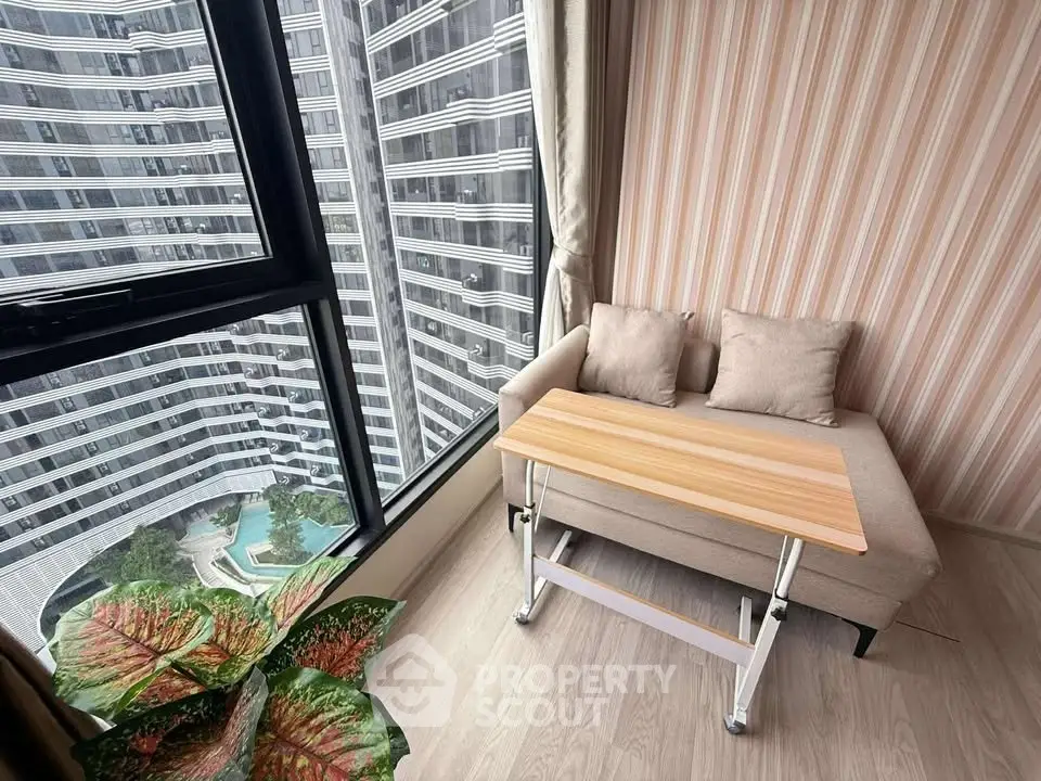 Modern apartment with cozy seating and stunning city view from large window.