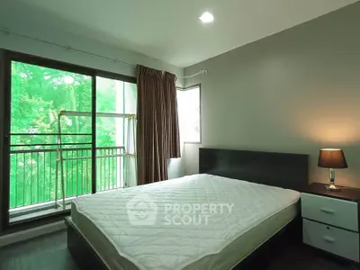 Cozy bedroom with large window and lush green view, featuring a comfortable bed and modern decor.