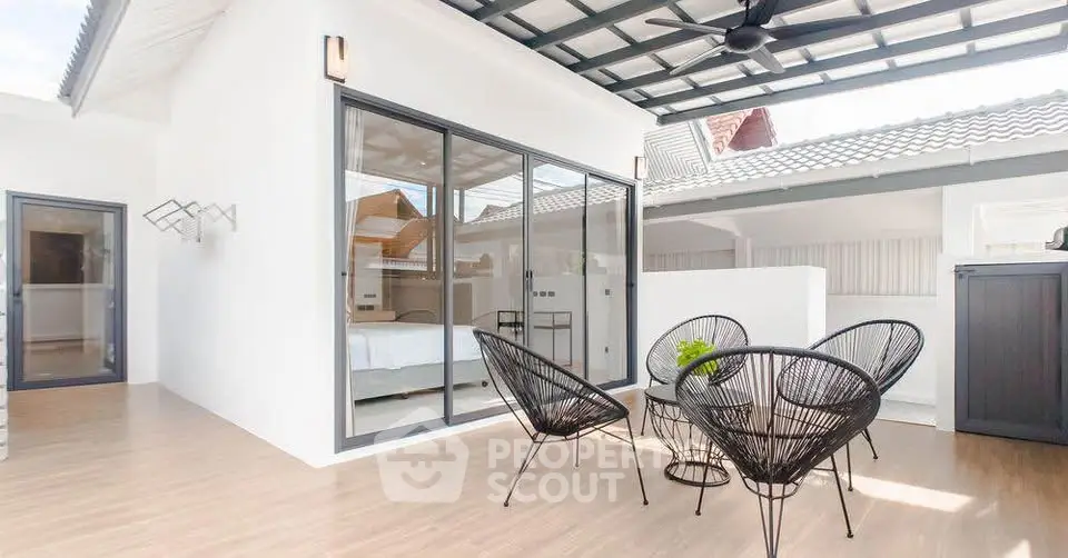 Modern rooftop terrace with stylish furniture and sliding glass doors leading to a bedroom.
